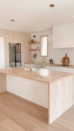 a large kitchen with an island in the middle and wooden flooring on the other side