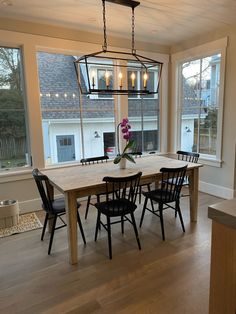 a dining room table with four chairs and a chandelier hanging from the ceiling