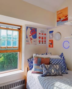 a bed sitting under a window next to a wall with pictures hanging on the walls