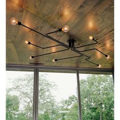 a room that has some lights on the ceiling and windows in front of it with trees outside