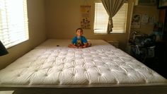 a young boy sitting on top of a white mattress