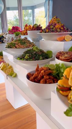 several bowls filled with food sitting on top of a white counter next to a window