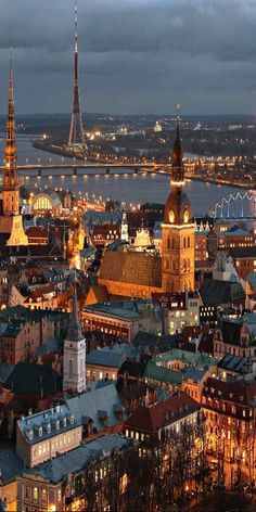 an aerial view of a city at night with lights on and bridges in the background