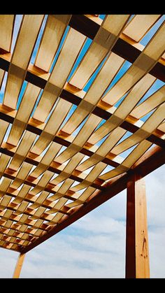 a bench under a wooden pergol with blue sky in the background