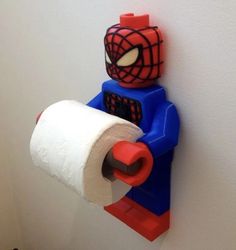 a spiderman toilet paper dispenser is on the wall next to a roll of toilet paper