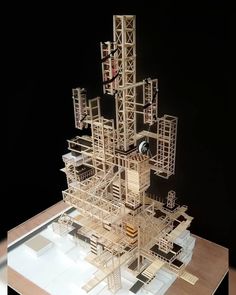 a model of a building made out of wood and metal parts on a table with a black background