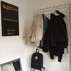 there is a backpack hanging on the wall next to clothes and other items in front of a mirror