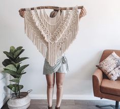 a woman standing in front of a chair holding up a shawl