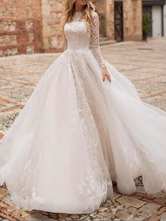 a woman in a wedding dress standing on a cobblestone street