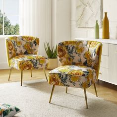 two chairs with floral upholstered cushions sit in front of a white rug and window