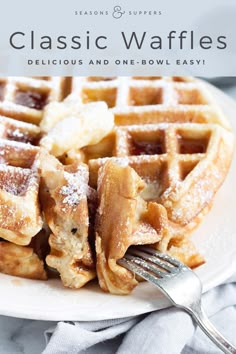 a white plate topped with waffles covered in powdered sugar next to a fork