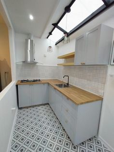 an empty kitchen with white cabinets and wood counter tops, tile flooring and skylights