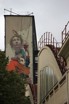 a large billboard on the side of a building in front of some trees and stairs