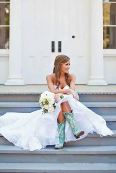 a woman in cowboy boots is sitting on the steps wearing a wedding dress and holding a bouquet