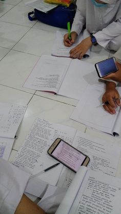 several people sitting at a table with papers and cell phones on top of each other