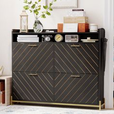 a black cabinet with gold trim and drawers in a living room next to a potted plant