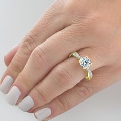 a woman's hand with a diamond ring on her finger and white manicured nails