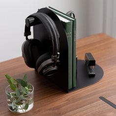 a book and headphones sitting on a table next to a vase with a plant