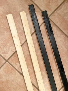 three pieces of wood sitting on top of a tile floor next to a pair of scissors