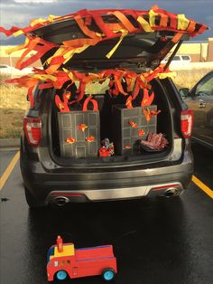 the trunk of a car is decorated with orange streamers and bags for children's birthdays