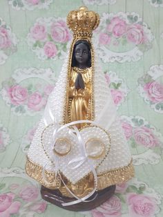 a small statue is sitting on top of a table with pearls and ribbon around it