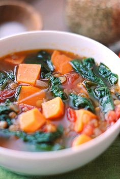 a bowl of soup with carrots, chickpeas and spinach in it