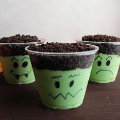 three plastic cups with dirt in them and faces drawn on the inside, sitting on a table