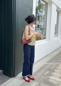 a woman standing in front of a store window looking at her cell phone while wearing red shoes