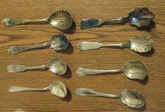 a collection of silver spoons sitting on top of a wooden table