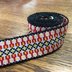 a close up of a ribbon on a wooden table with a black and red design