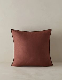 an orange and brown pillow on a white surface