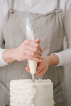 a woman is decorating a white cake with icing on the top and bottom