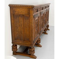 an old wooden cabinet with carvings on the front and sides, sitting against a white wall