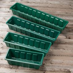 three green plastic bins sitting on top of a wooden floor next to each other