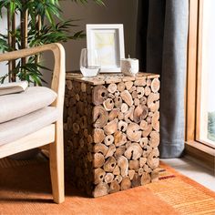 a chair and table with logs stacked on top of each other in front of a window