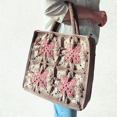 a woman carrying a crocheted purse with pink flowers