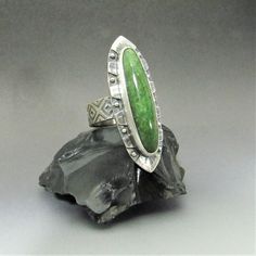 "Unique, eye catching nephrite jade ring is a one of a kind design in Argentium sterling silver and traditional sterling silver. A beautiful long slim jade cabochon is the star of this Aztec Mesoamerican inspired design. Jade was an integral component of Mesoamerican design and adornment, which is why as soon as I saw the stone there was a feeling of something from pre-Columbian times.  As the design coalesced in mind and matter, I soon realized the resemblance to the Azetc obsidian sword or Mac Unique Oval Jade Rings, Unique Sterling Silver Emerald Ring With Polished Finish, Unique Sterling Silver Emerald Ring Collectible, Unique Collectible Sterling Silver Emerald Ring, Nephrite Jade, Jade Ring, Art To Wear, Inspired Jewelry, Jewelry Maker