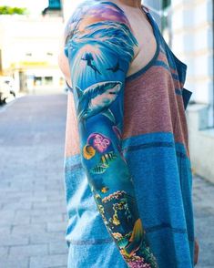 a man with a tattoo on his arm is standing in front of a brick sidewalk