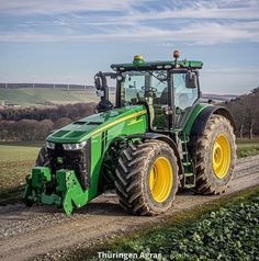 a green tractor driving down a dirt road