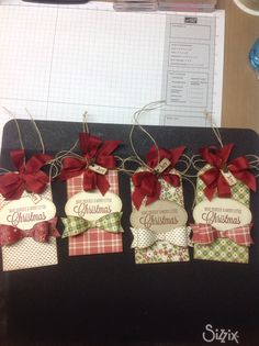 four tags with bows are hanging on a table next to a notepad and pen