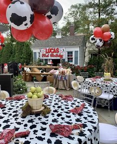 a table with black and white polka dot cloth on it, red balloons in the shape of soccer balls