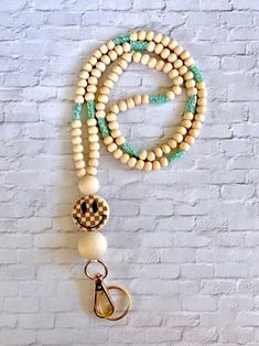 a white and green beaded necklace hanging on a wall next to a pair of scissors