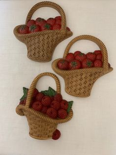 three woven baskets filled with strawberries on top of a white table next to each other