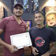 two men standing next to each other in front of paintings and holding a cheque