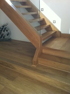 a wooden stair case with glass railing on top and wood flooring in the bottom