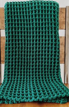 a green crocheted blanket sitting on top of a wooden chair