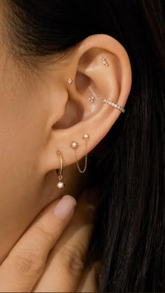 a close up of a person wearing ear piercings with pearls on the end of their ears