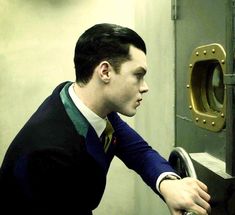 a man in a suit and tie leaning against a door