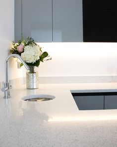 a vase with flowers sitting on top of a kitchen counter next to a faucet