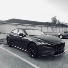 black and white photo of a car parked in a parking lot next to a building